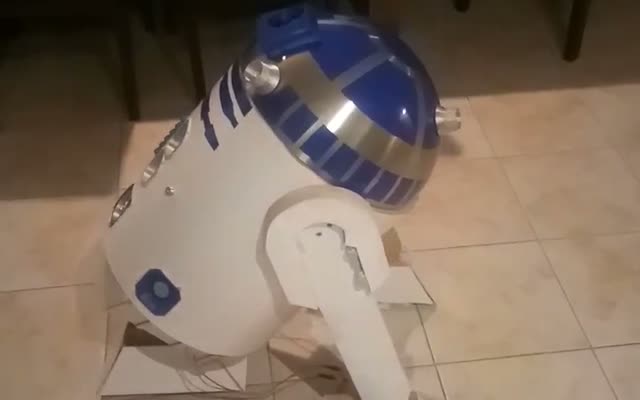A homemade R2-D2 on a tiled floor